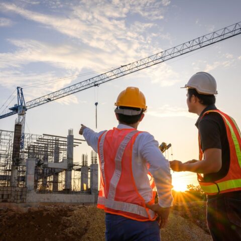two construction workers pointing at a construction building